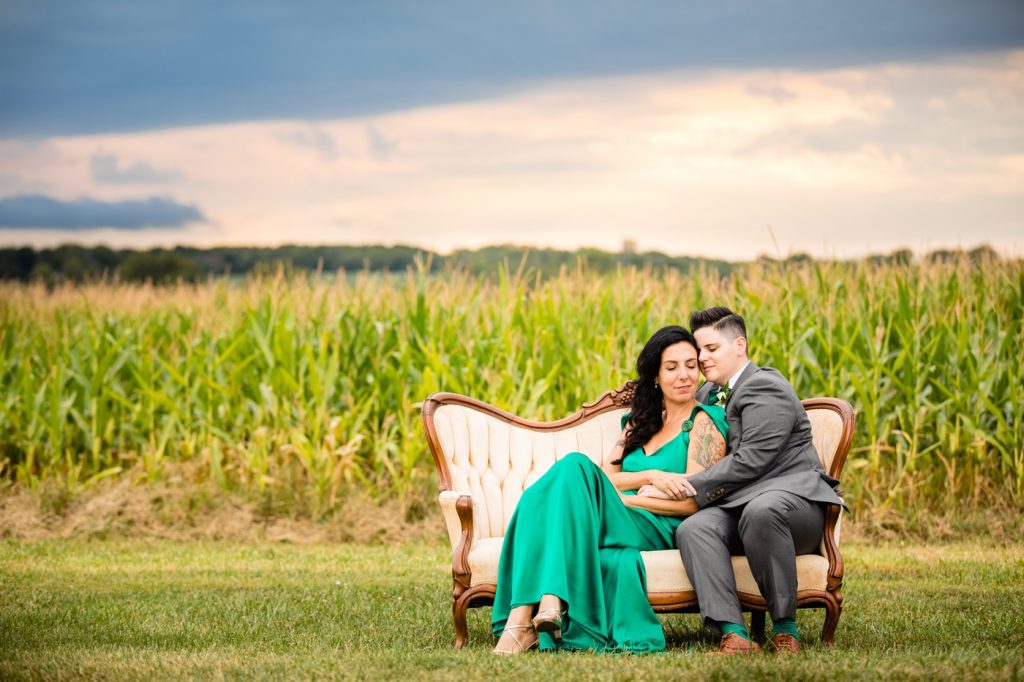 a couple on a couch in a corn field at awedding at Wren Farm