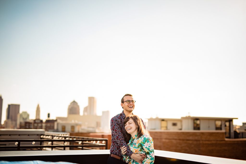 a couple laughs on their rooftop balcony overlooking the city of Columbus