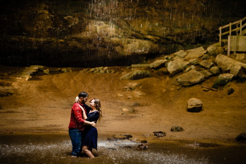 a couple hugs under the waterfall at Ash Cave during their engagement photos at Hocking Hills