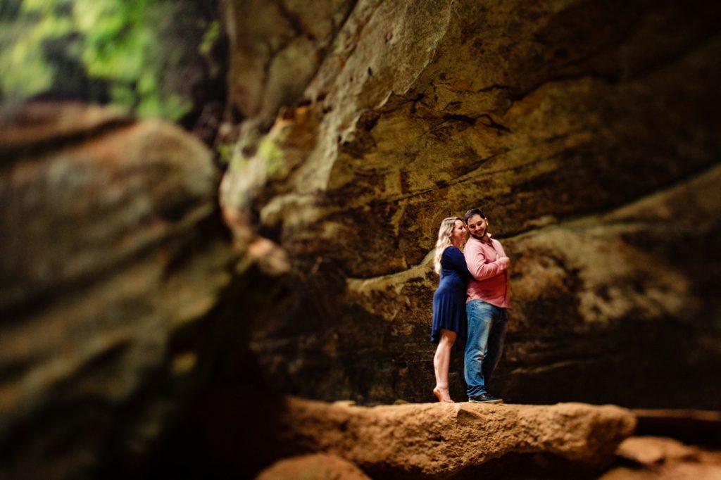 a couple cuddles and laughs among the boulders during their engagement photos at Hocking Hills