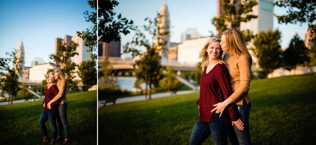 a LGBTQ couple pose in front of the Columbus skyline during their engagement photos at Bicentennial Park