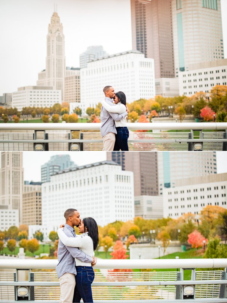 a couple poses in front of the Columbus skyline during their engagement photos at the Scioto Mile