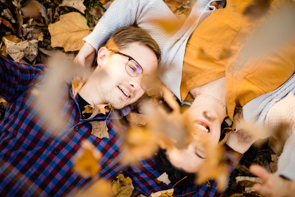 a couple has a leaf fight during their fall engagement photos in German Village