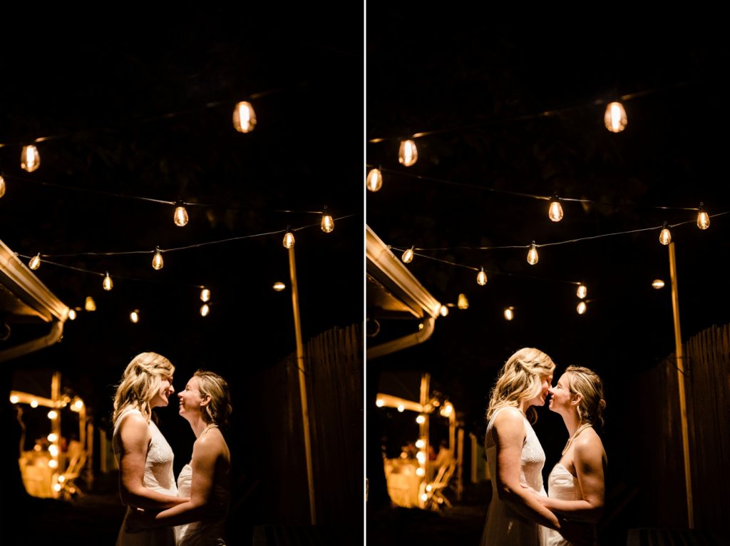 two brides cuddle beneath the string lights at their intimate backyard wedding reception