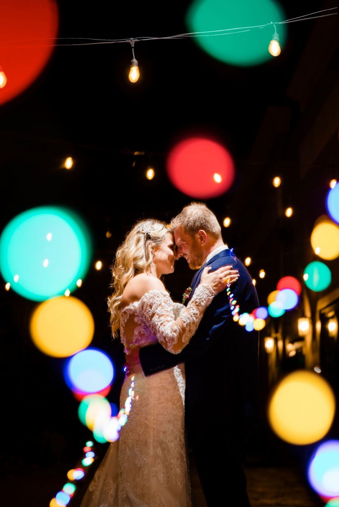 a bride and groom pose with Christmas lights at their Brookshire wedding