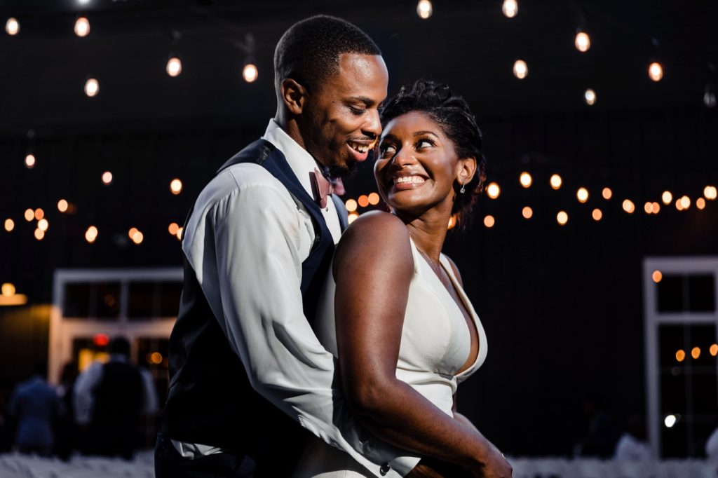 a bride and groom pose under string lights after their wedding at The New Albany Estate
