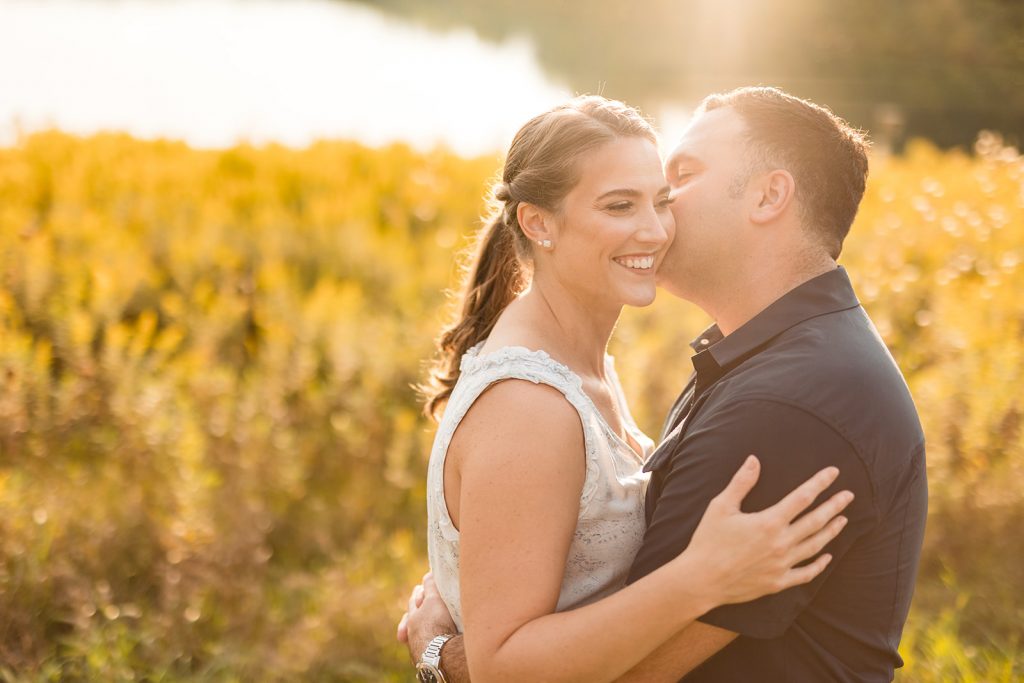 a couple snuggles in front of golden rod during their engagement photos at Prairie Oaks Metro Park