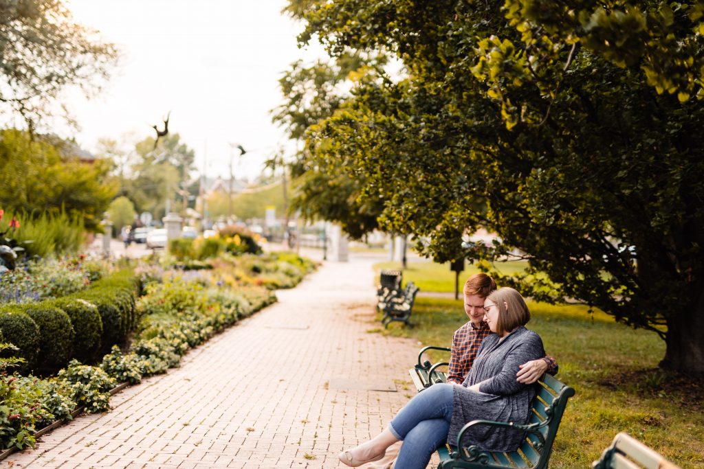 a couple sits on a bench at Schiller Park during their German Village engagement photos