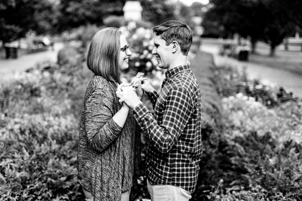 a couple holds hands in front of flowers during their German Village engagement photos