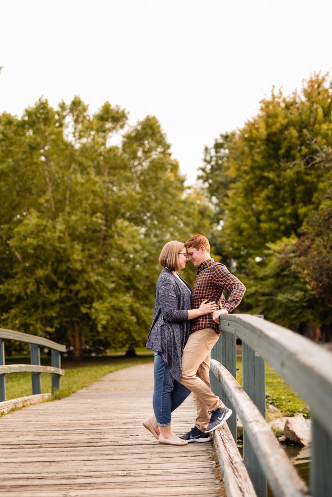 a couple cuddles on the bridge at Schiller Park during their German Village engagement photos