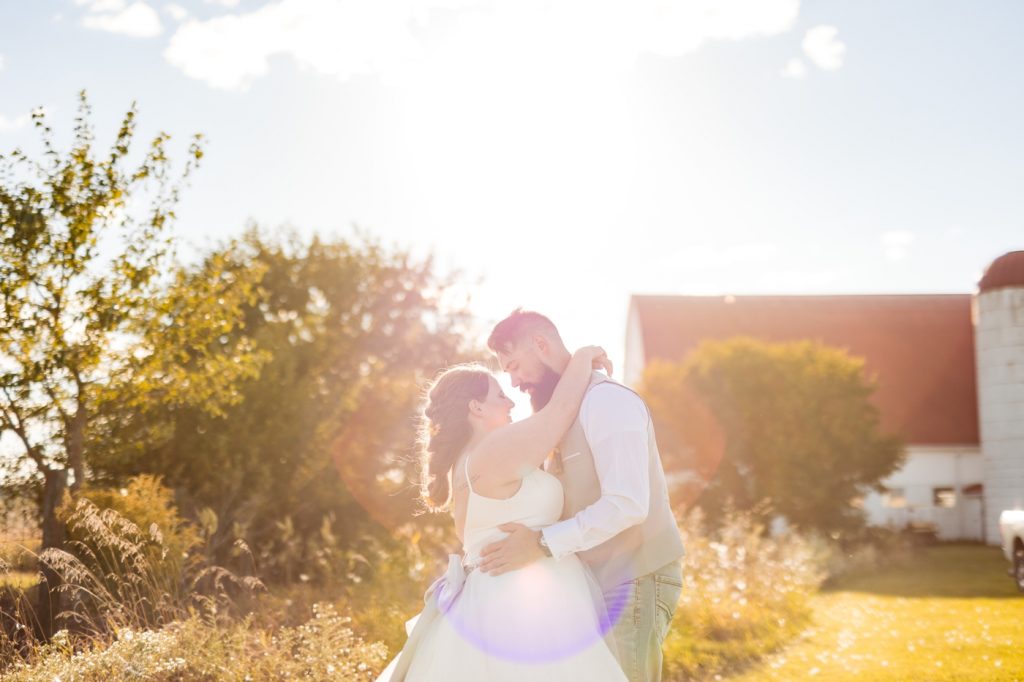 a bride and groom pose in front of the sunset after their Wren Farm wedding