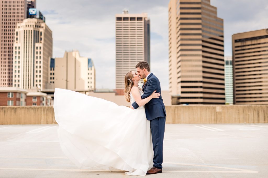 a couple kiss in front of the Columbus skyline before their wedding at Edison 777