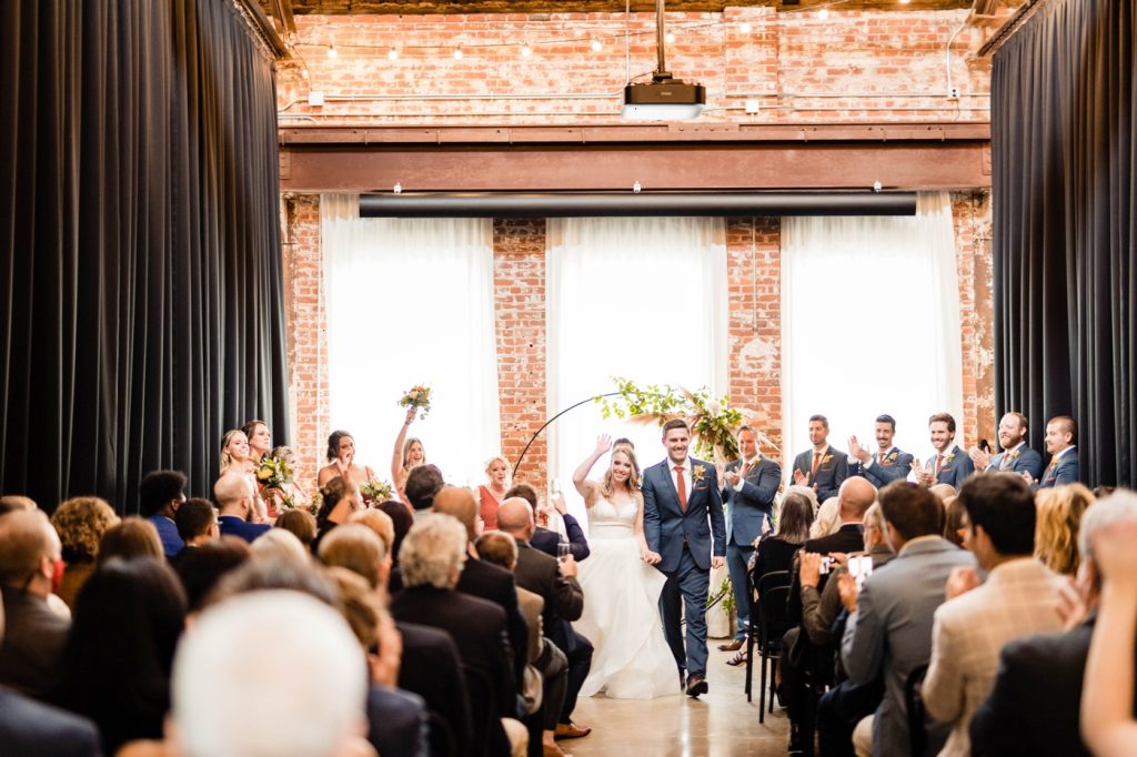 a couple walks up the aisle after their wedding at Edison 777