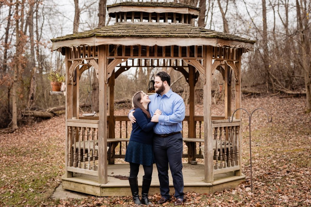 a couple poses in front of a gazebo during their engagement photos in Lancaster