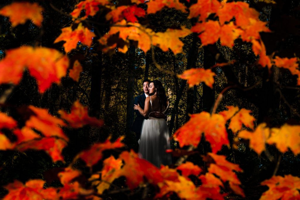 a bride and groom among orange leaves for their fall wedding at The Exchange at Bridge Park