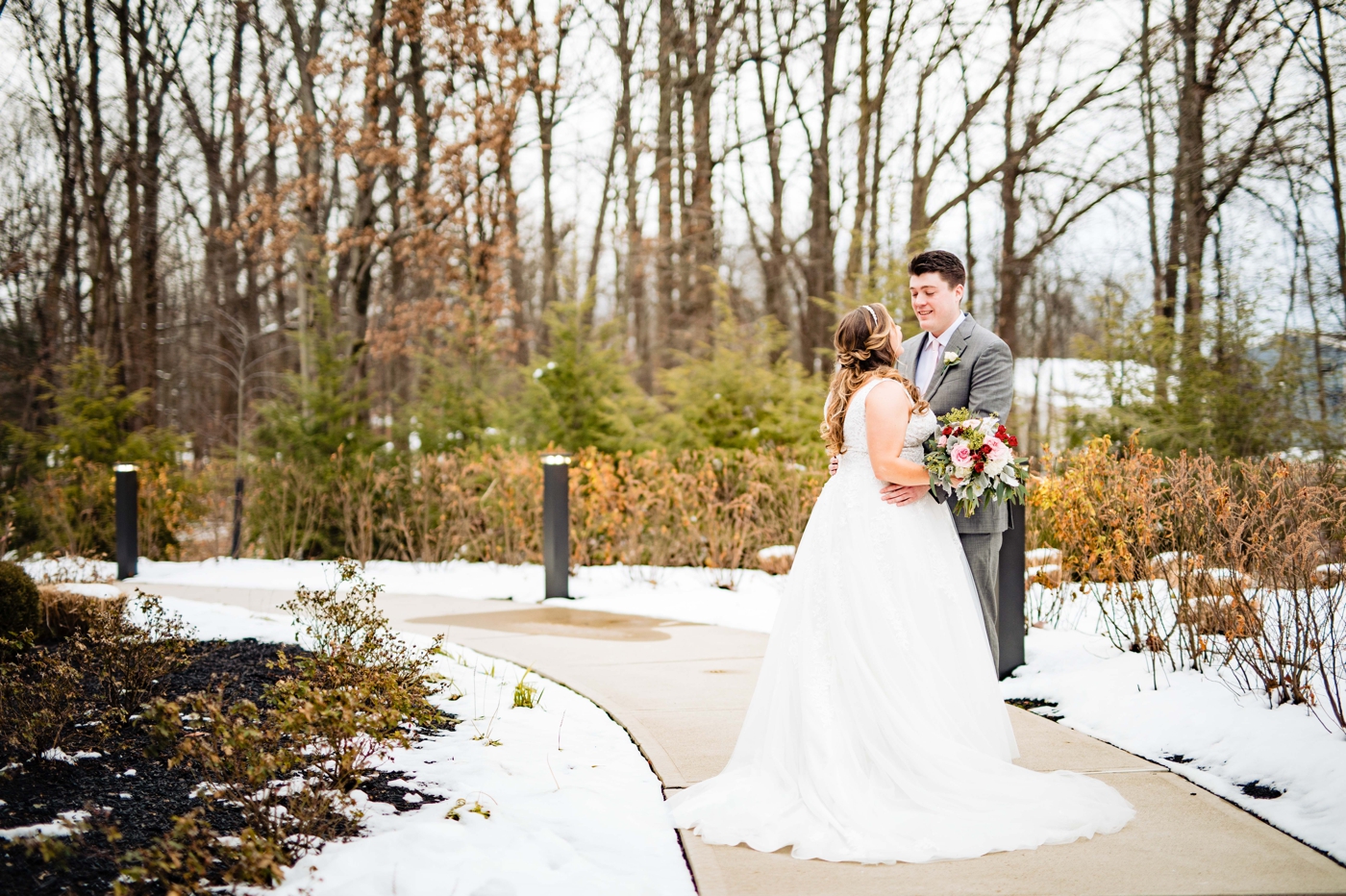 a couple poses in the snow before their wedding in New Albany