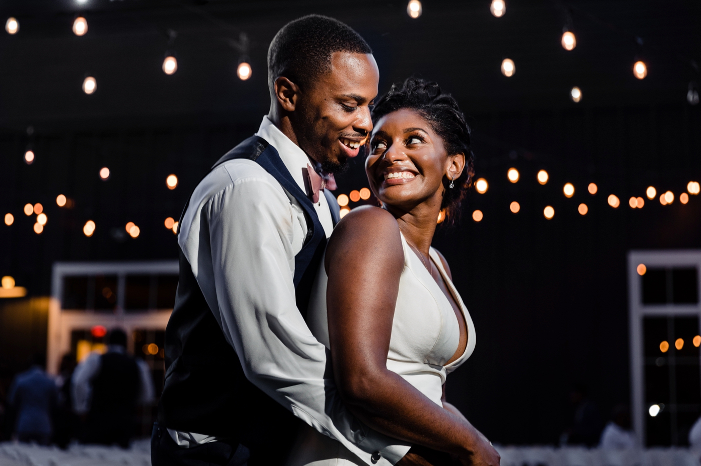 a bride and groom pose under string lights after their wedding at The New Albany Estate