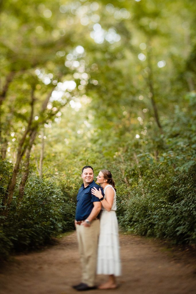 a woman snuggles her fiance in the woods during their engagement photos at Prairie Oaks Metro Park