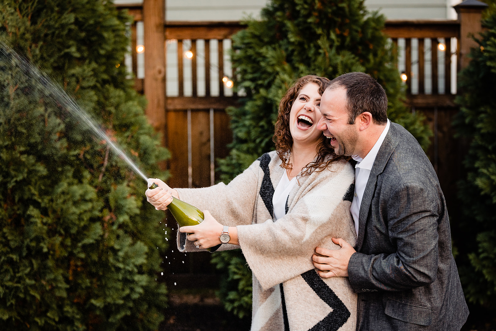 a couple laughs while spraying champagne during their engagement photos in Worthington