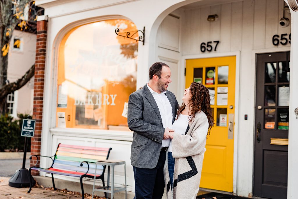 a couple laughs in front of the colorful buildings during their engagement photos in Worthington