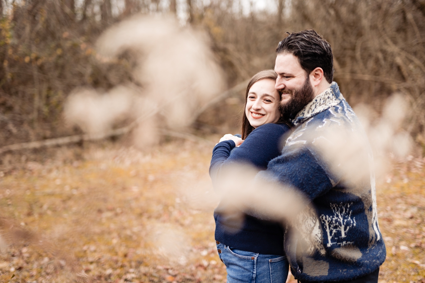 a couple snuggles in the weeds during their engagement photos in Lancaster