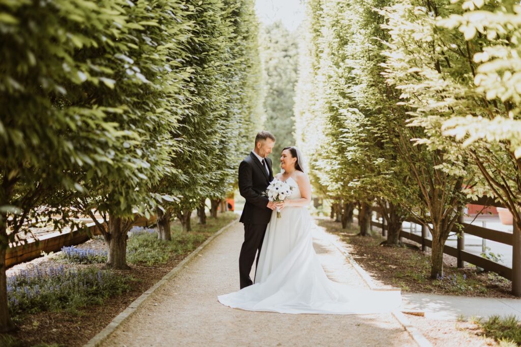 a couple poses among the evergreens before their wedding at Franklin Park Conservatory